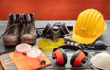 Protective Equipment Work safety protection equipment. Industrial protective gear on wooden table, red color background. Construction site health and safety concept